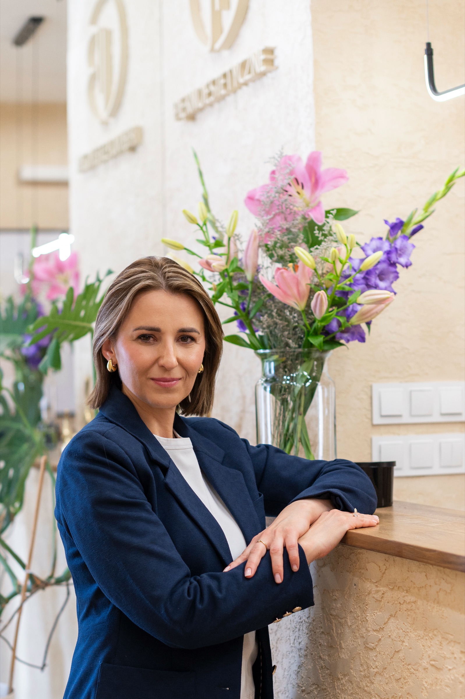 Dorota Bazan przy recepcji, na ścianie za nią przestrzenne logo Piękno Estetyczne