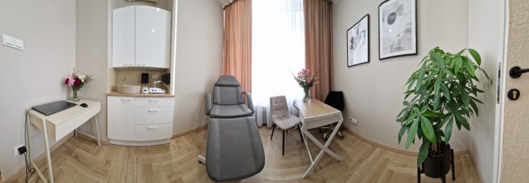 Panoramiczne ujęcie gabinetu zabiegowego nr 1: fotel kosmetyczny, stanowisko z umywalką i biurko