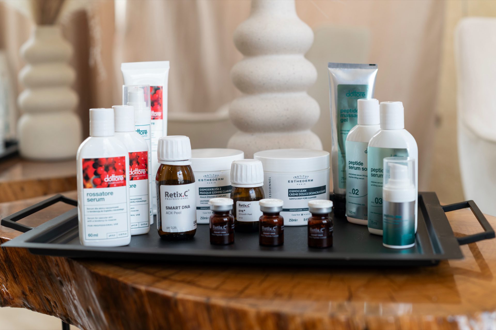 Kosmetyki profesjonalne Dottore, Retix.C i Institut Esthederm na tacy postawionej na drewnianym stoliku