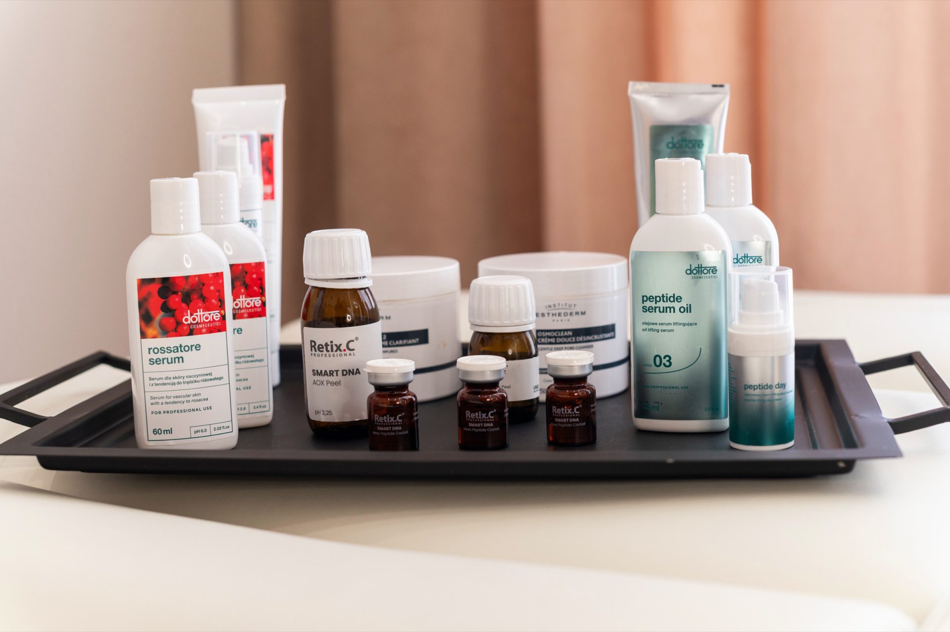 Zestaw kosmetyków profesjonalnych Dottore, Retix.C i Institut Esthederm na tacy, w tle beżowa zasłona