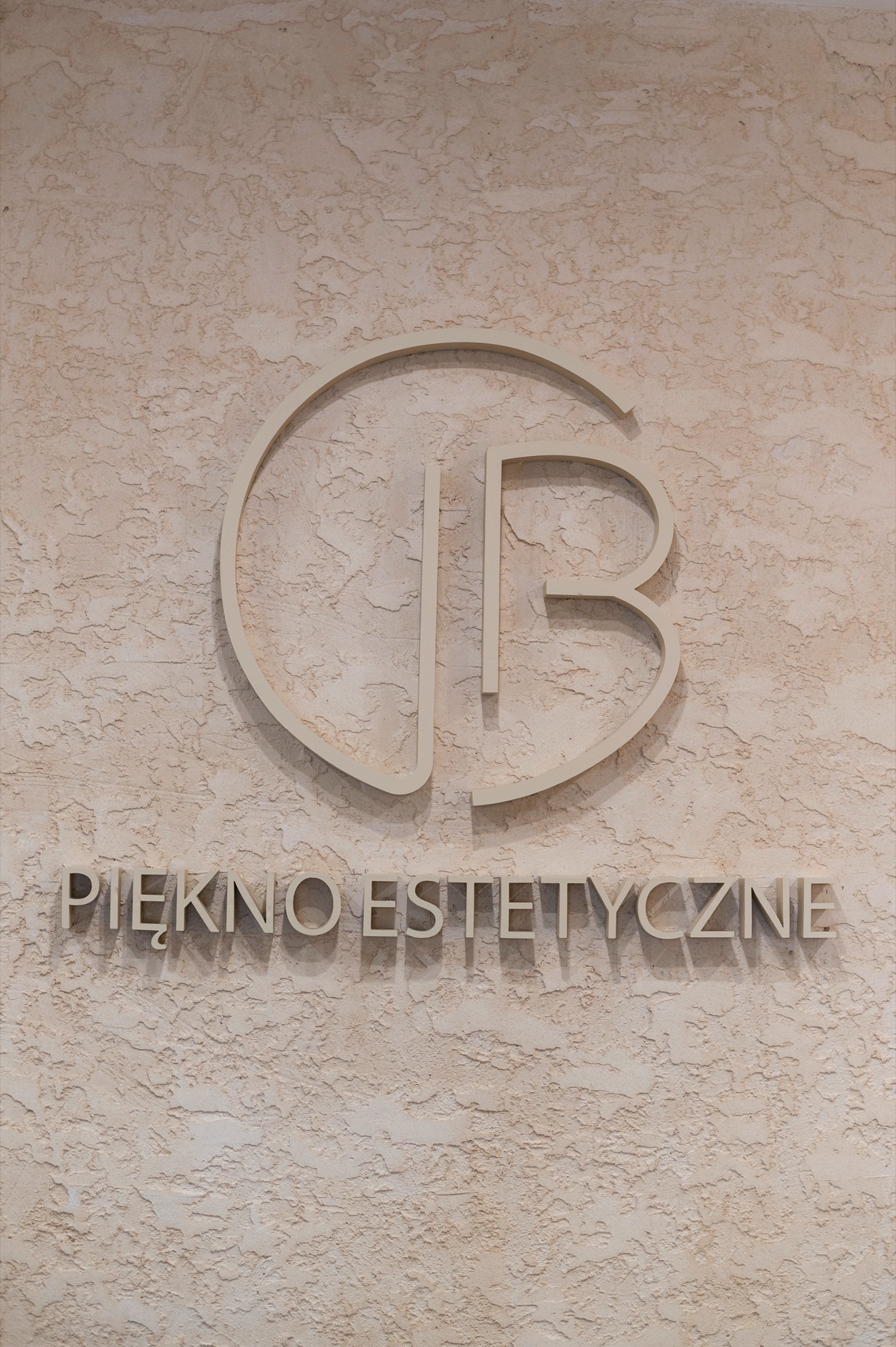 Przestrzenne logo Piękno Estetyczne na strukturalnej ścianie recepcji, kadr pionowy