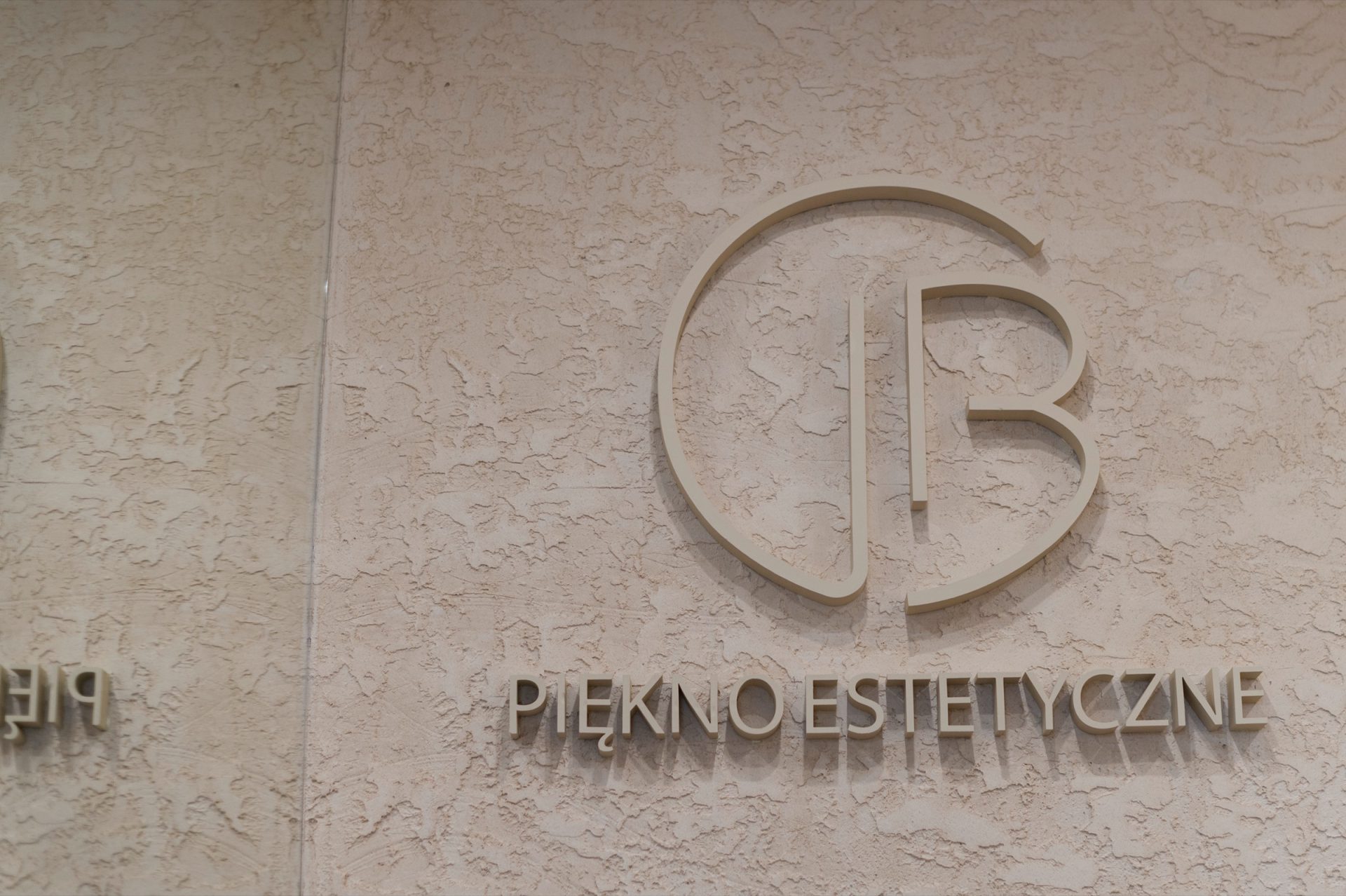 Przestrzenne logo Piękno Estetyczne na strukturalnej ścianie recepcji, kadr poziomy